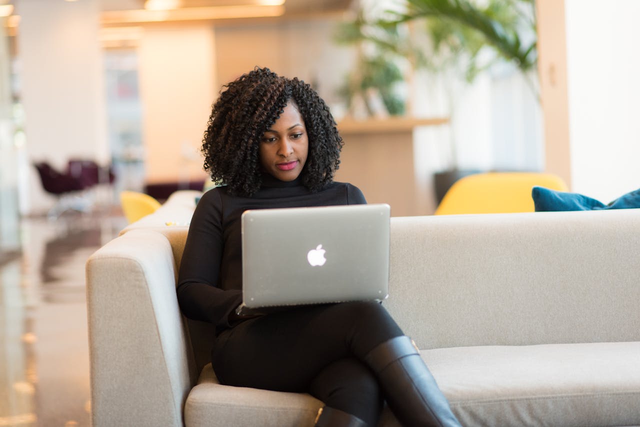 An African American woman working remotely on a laptop in a modern indoor setting.